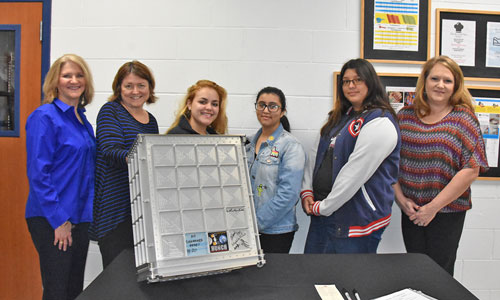 Chosen students hold up the signed stowage locker with Fashion Design teacher and NASA HUNCH manager.